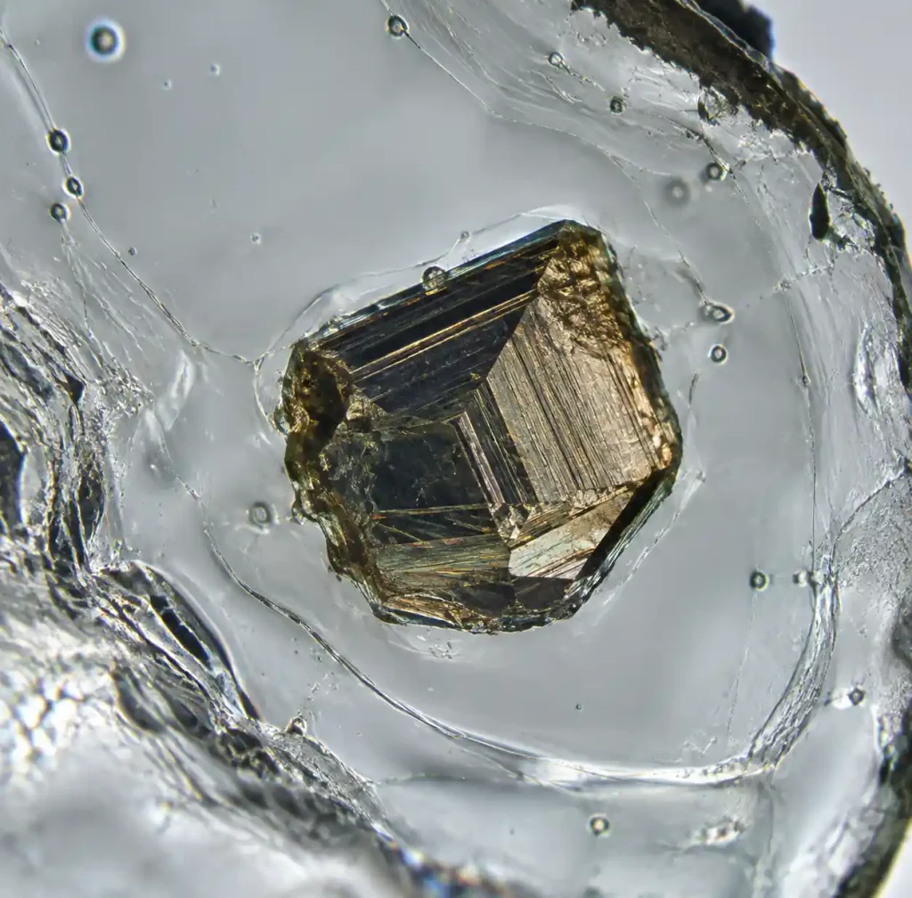 Microscopic nickel sulfide inclusion in tempered glass showing crystal structure